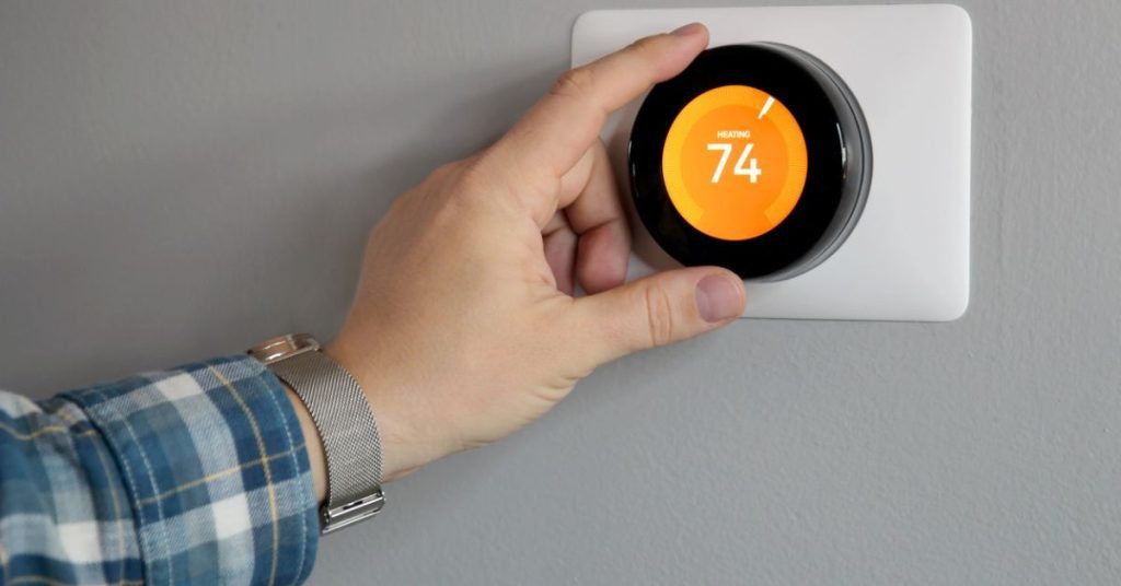 Man's hand adjusting thermostat to 74º