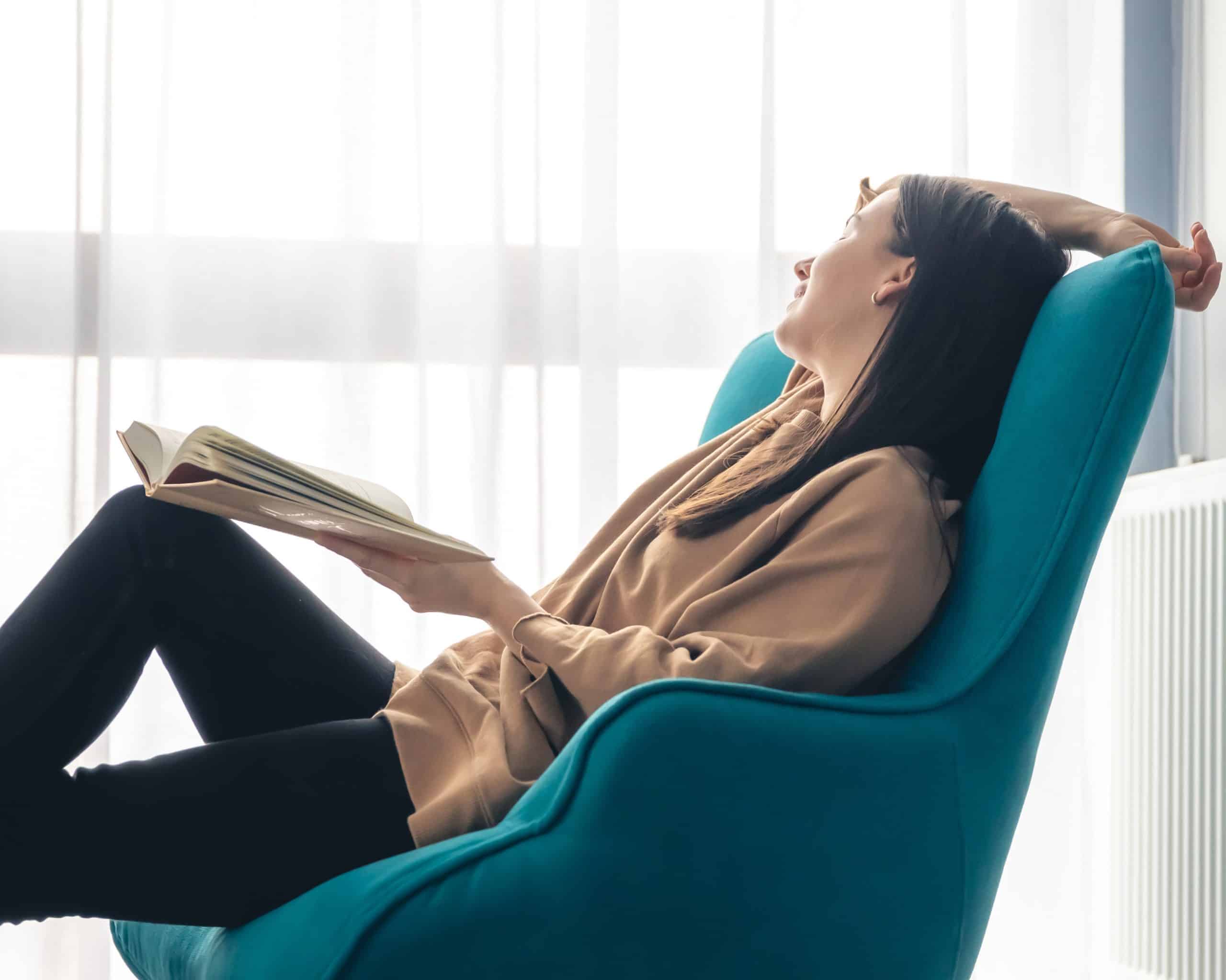 Woman smiling leaning back in chair holding a book